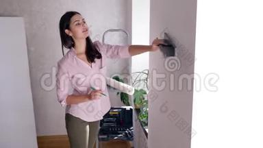 维修公寓，可爱的女人在装修房子的时候重新装修，把架子挂在墙上